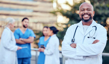 Theres nothing you cant fix with a smile. Shot of a mature male doctor standing with her arms...