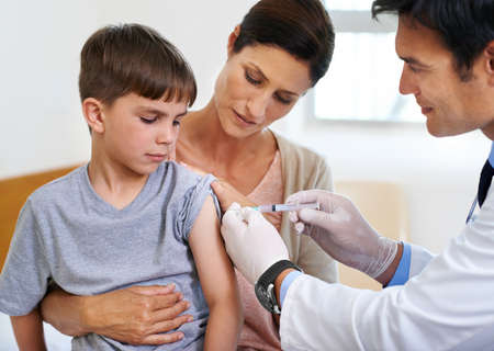 Hope this shot gives me super powers. Shot of a brave young boy receiving an injection in his arm.の写真素材
