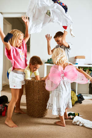 Its raining clothes. Shot of little siblings throwing laundry in the air at home.の写真素材