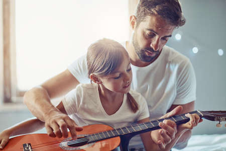 Showing her how to express her feelings through music. Shot of a little girl playing the guitar with her father.の写真素材
