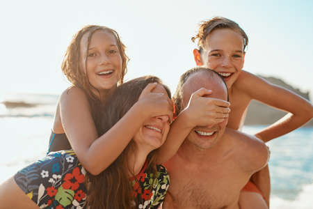 Its all fun and games at the beach. Cropped shot of a couple and their two kids spending the day at the beach.の写真素材