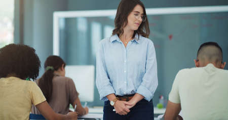 It takes one person to believe. Shot of an attractive professor watching her students complete their exams at university.の写真素材