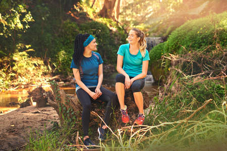 Catching up while catching our breath. Shot of two sporty young women taking a break while out...
