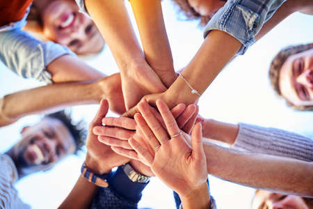 We are stronger united. Low angle shot of university students standing outside with their hands together.の写真素材