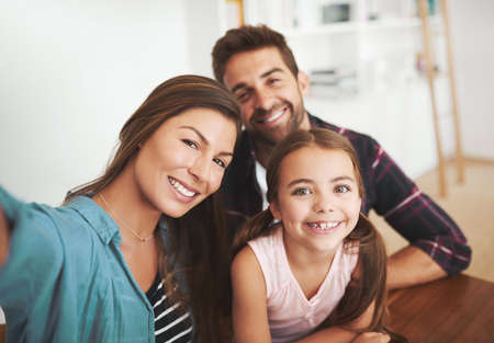 This family isnt selfie shy. Portrait of a happy married couple and their young daughter posing for...