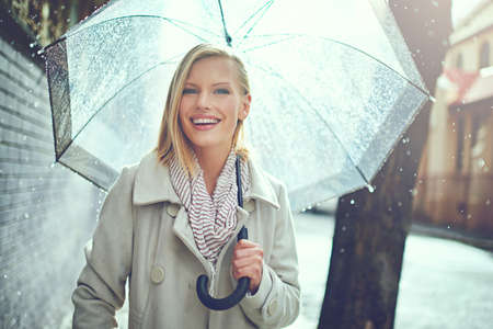 This weather wont get me down. Cropped portrait of an attractive young woman walking in the rain.の写真素材