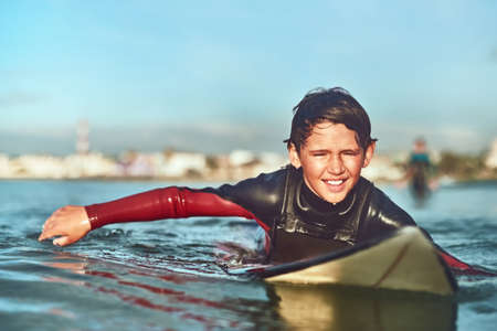 Youre never too young to surf. Shot of a young boy out surfing.の写真素材