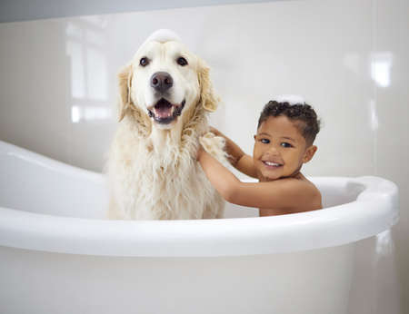 Were clean boys. Shot of an adorable little boy sitting in the bathtub with his Golden Retriever...