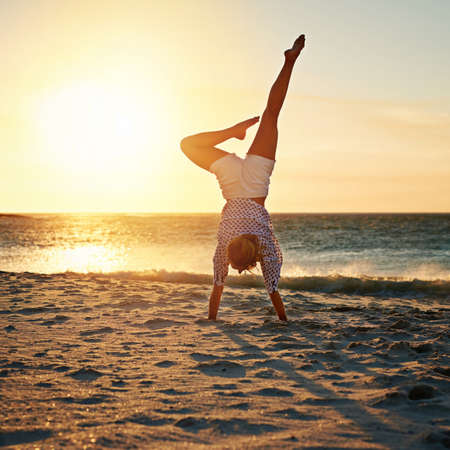 The best place to practice her yoga skills. Shot of an unecognizable woman on the beach.