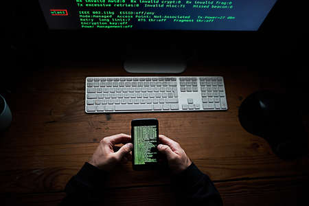 Not even your smartphone is safe. High angle shot of an unidentifiable hacker using a computer late...