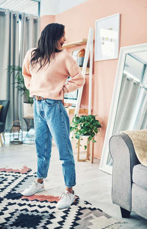 These denims are definitely my new favourite. Shot of a young woman looking at herself in the mirror...