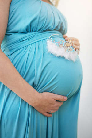 Mommy loves you, little princess. Shot of an unidentifiable pregnant woman holding a tiara against her belly.の写真素材