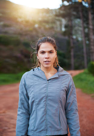 This trail doesnt know it yet, but its owned. Shot of a young woman out for a trail run.の写真素材
