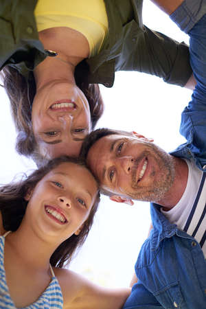 Family huddle. Low angle shot of a young family standing in a huddle outside.の写真素材