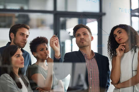 Looking at the numbers from all angles. Shot of a well dressed businesswoman giving a presentation to her colleagues in the boardroom.の写真素材