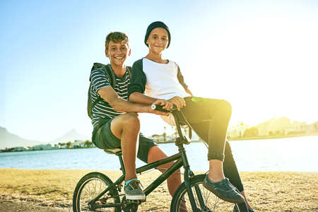 Taking my brother for a ride. Cropped portrait of a young boy giving his younger brother a lift on a bicycle outside.