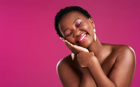Smile a while and give your face a rest. Studio shot of a beautiful young woman posing against a pink background.の写真素材
