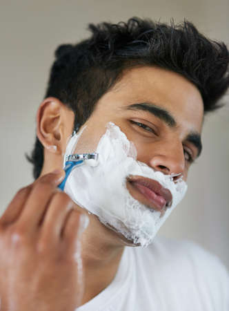 No shave November is done. Shot of a handsome young man shaving his facial hair in the bathroom.の写真素材