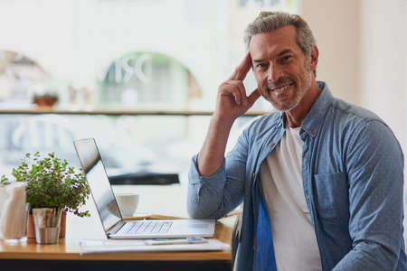 The cafe that supports my work and leisure needs. Portrait of a handsome mature man using a laptop...