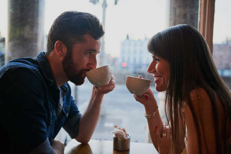 Connecting over coffee. Cropped shot of an affectionate young couple sitting in a coffee shop while on a date.の写真素材