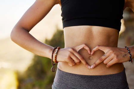 Its your body, take care of it. Cropped shot of a young woman forming a heart shape over her...