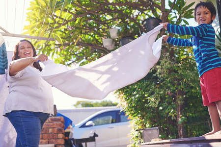 Hes mommys little helper. Portrait of a mother and son holding a towel out on the ends together.