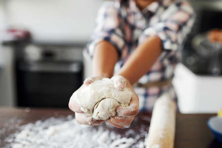 Shaping made fun. Cropped shot of an unrecognizable girl having fun while baking in the kitchen at home.の写真素材
