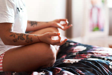 Practise yoga for peace of mind. Cropped shot of an unrecognizable woman practising yoga at home.の写真素材