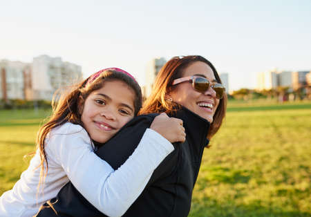 Weekends are for days at the park. Portrait of a young girl bonding with her mother at the park.の写真素材