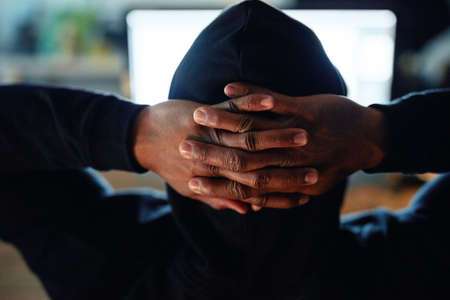 Theyll never catch me. Rearview shot of an unidentifiable hacker cracking a computer code in the...