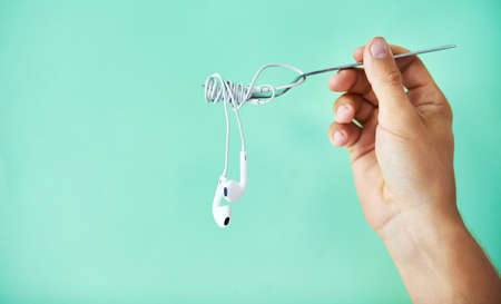 Serving up some soul food. Cropped studio shot of a man holding earphones wrapped around a fork against a turquoise background.の写真素材