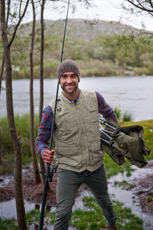 Fishing - his idea of fun. Portrait of a handsome young man enjoying his fishing trip.の写真素材