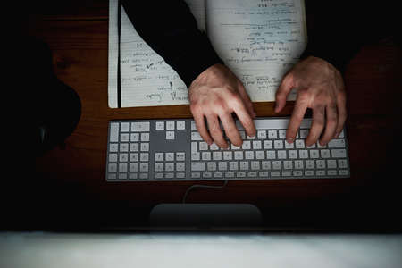 Doing what he does best. High angle shot of an unidentifiable hacker using a computer late at night.