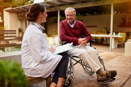Thats great news, doc. Shot of a young doctor and her elderly patient talking while sitting outside.