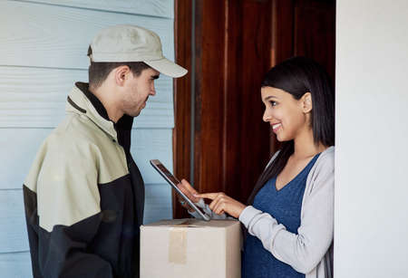 Logging her delivery as received. Cropped shot of a young woman using a digital tablet to sign for...