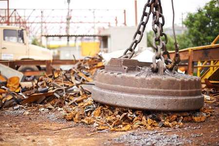 Power of magnetics. Cropped shot of a large magnet collecting garbage at a scrapyard.の写真素材