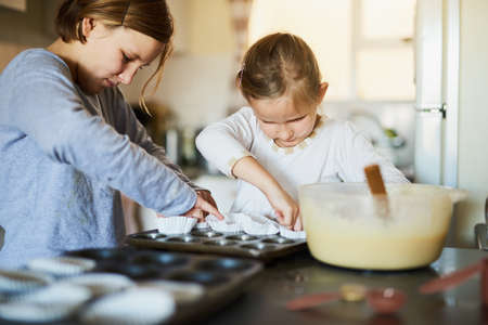 Love and care are their secret ingredients. Cropped shot of two young siblings baking together at home.の写真素材