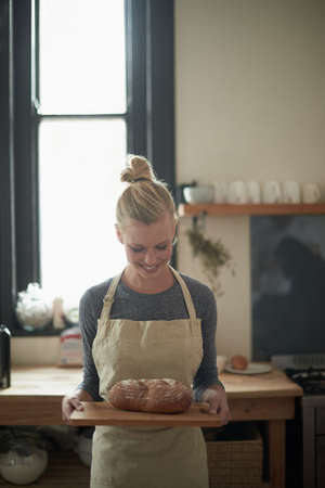 The perfect loaf. Shot of a young female baker with homemade bread.の写真素材