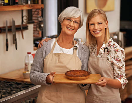 Bonding over baking. Shot of a young woman and her grandmother showing off their baking skills.の写真素材