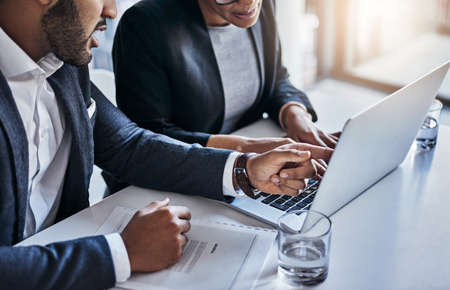 Technology improves the quality of their work. Shot of two businesspeople working together on a laptop in an office.の写真素材