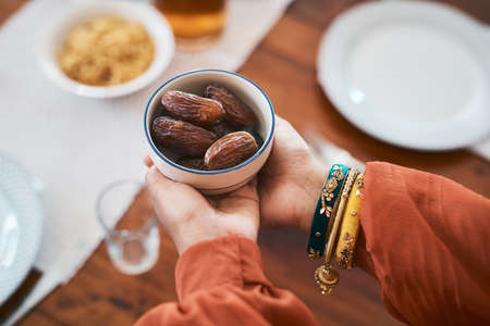 Breaking my fast the traditional way. Shot of a muslim woman holding a bowl of dates to break her fast.の写真素材