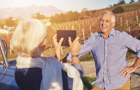 Making memories. Cropped shot of a senior woman taking a photo of her husband while on a roadtrip.