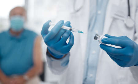 The first batch of vaccinations is being rolled out. Cropped shot of an unrecognizable male doctor preparing the covid 19 vaccination for a patient.の写真素材