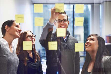 We should put our ideas together. Cropped shot of a group of businesspeople brainstorming on a glass...