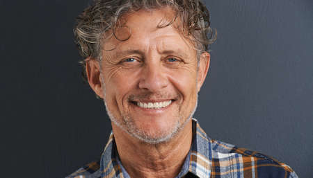 A handsome smile. A cropped portrait of a happy mature man standing against a grey background.