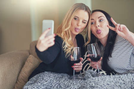 Life is better when youre crazy together. Shot of two young friends taking a funny selfie together...