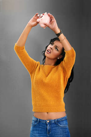 I dont remember putting invisible coins in here. Studio shot of a young woman looking up at her...