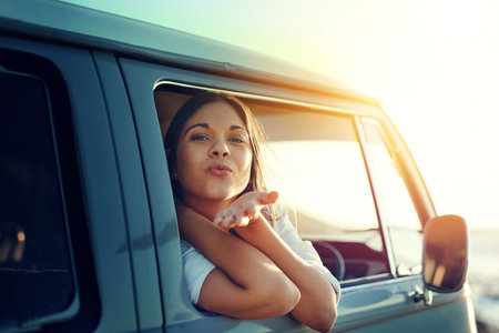 Mwah See ya when I get back. Shot of a young woman leaning out of a vans window and blowing a kiss...