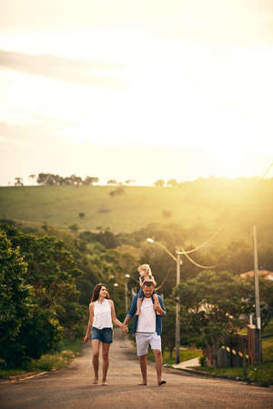 Enjoy the simple things with the ones you love. Shot of a young family taking a walk down the road outside.の写真素材