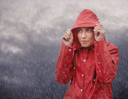Wow, Im glad I wore my raincoat. Cropped shot of an attractive young woman standing in the rain.の写真素材